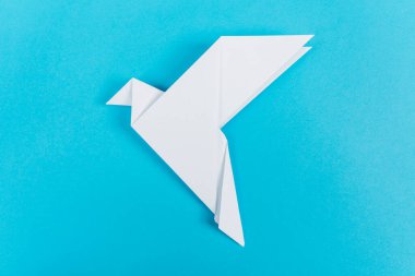 Origami güvercinleri kırmızı bir kalple, aşkın, birliğin ve barışın sembolü, mavi bir arka planda..