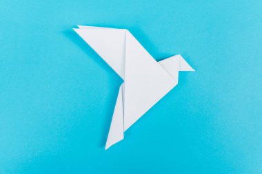 Origami güvercinleri kırmızı bir kalple, aşkın, birliğin ve barışın sembolü, mavi bir arka planda..