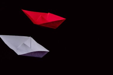 Kağıt tekneler liderliği ve siyah arka planlı beyaz ve kırmızı giyen kalabalığın önünde durmak..