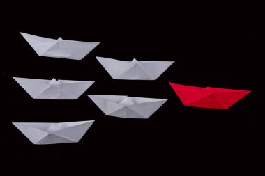 Kağıt tekneler liderliği ve siyah arka planlı beyaz ve kırmızı giyen kalabalığın önünde durmak..