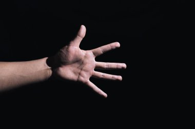 Yapay ışıkla aydınlatılmış siyah arkaplanlı el işaretleri