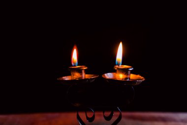 Bir şamdanda yanan ve yanmayan mumlar karanlık bir arka plana karşı, sıcaklık ve hatırayı çağrıştırıyor..