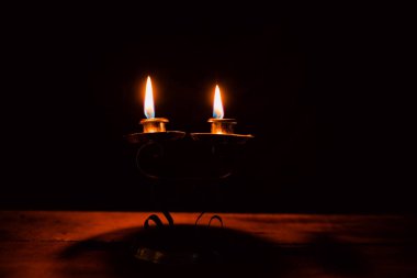 Bir şamdanda yanan ve yanmayan mumlar karanlık bir arka plana karşı, sıcaklık ve hatırayı çağrıştırıyor..