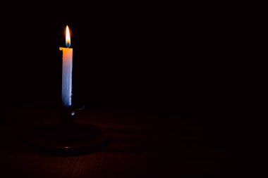 Bir şamdanda yanan ve yanmayan mumlar karanlık bir arka plana karşı, sıcaklık ve hatırayı çağrıştırıyor..