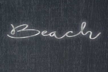 A blackboard with a handwritten chalk message that says beach, a powerful symbol of business success and motivation in educational and production concepts.