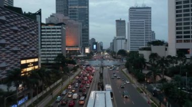 Jakarta şehrinin havadan görünüşü - Endonezya 'nın hareketli başkentinin geniş ve canlı bir perspektifi. Kamera şehrin üzerinde süzülerek modern gökdelenlerin, tarihi binaların ve genişleyen yerleşim alanlarının dinamik bir karışımını ortaya çıkarıyor..