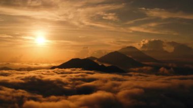 Dağların üzerinde gün doğumunun ve kalın bulutların havadan görünüşü görkemli bir dağ sırasının üzerinde yeni bir günün nefes kesici ve dingin perspektifi..