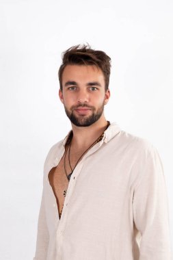 Young handsome bearded man in white shirt against white studio background clipart