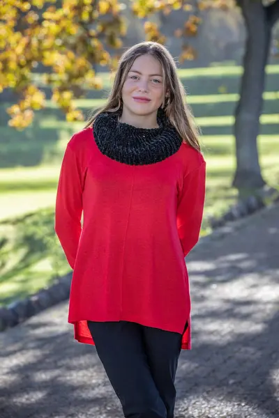 stock image Young blonde woman donning red sweater, standing enchantingly beneath the autumn trees