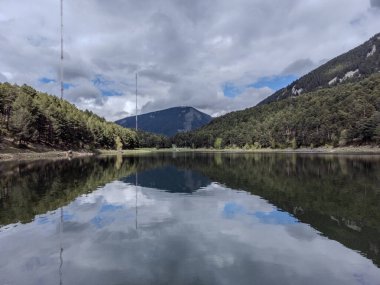 Ormanın içindeki ayna gölü. Engolasters Gölü, Andorra.