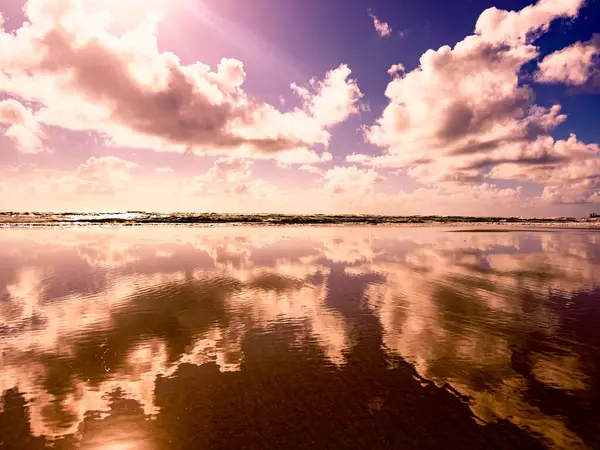 Bulutlar sakin denizi yansıtıyor.