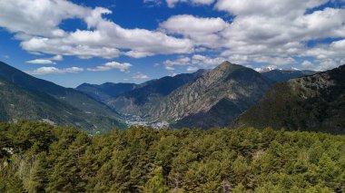 Önünde ağaçlar olan güzel bir dağ sırası. Göl sakin ve sakin, arka planda birkaç ağaç var. Dağlar karla kaplı, ortama huzur veriyor.