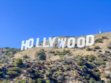 Hollywood tabelası bir tepede. Gökyüzü mavi ve berrak. İşaret büyük ve beyaz.