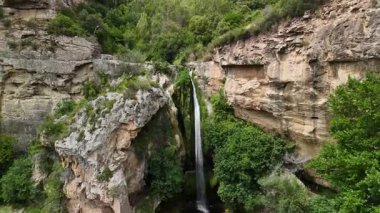 Bir şelale kayalık bir uçurumdan aşağı akıyor.