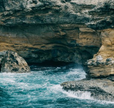 Rocky coastal cave with turquoise waters and rugged cliffs in Martinique, capturing the dramatic natural landscape of the Caribbean island clipart