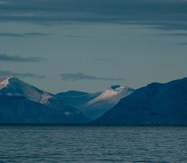 Snow-capped mountains with striations at dusk, Longyearbyen, Svalbard clipart