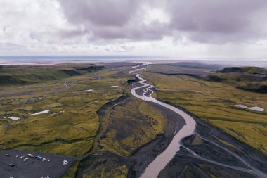 Güney İzlanda 'daki yeşil vadi ve dağlardan geçen kıvrımlı nehrin havadan görünüşü