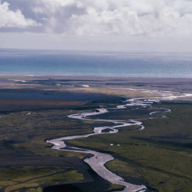 Güney İzlanda 'daki yeşil vadi ve dağlardan geçen kıvrımlı nehrin havadan görünüşü