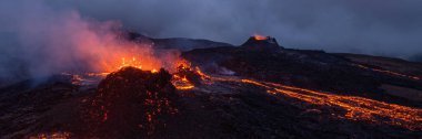 İzlanda 'daki Solheimajokull buzulunun havadan görünüşü, zıt yeşil tepeler ve parçalı bulutlu bir gökyüzünün altında buzul gölünün buluşması ile engebeli buz tabakasının birleşmesi..