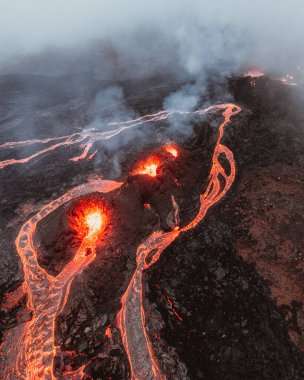 İzlanda 'daki Solheimajokull buzulunun havadan görünüşü, zıt yeşil tepeler ve parçalı bulutlu bir gökyüzünün altında buzul gölünün buluşması ile engebeli buz tabakasının birleşmesi..