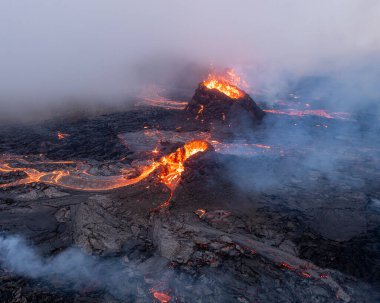 İzlanda 'daki Solheimajokull buzulunun havadan görünüşü, zıt yeşil tepeler ve parçalı bulutlu bir gökyüzünün altında buzul gölünün buluşması ile engebeli buz tabakasının birleşmesi..