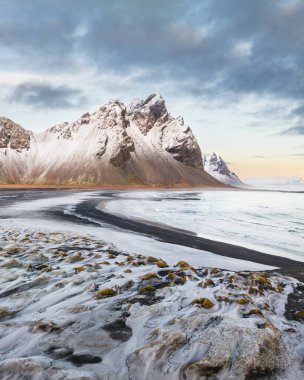 Snow-covered Vestrahorn mountain and icy landscape at Stokksnes beach, South East Iceland clipart