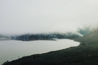 İzlanda 'daki Solheimajokull buzulunun sakin manzarası yansıtıcı bir buzul gölü ve karanlık volkanik araziyle kaplıydı..