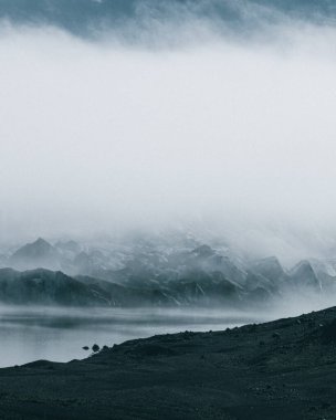 İzlanda 'daki Solheimajokull buzulunun sakin manzarası yansıtıcı bir buzul gölü ve karanlık volkanik araziyle kaplıydı..
