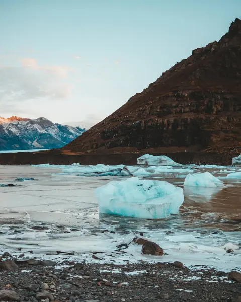 stock image Icy formations and frozen lake at Svinafellsjokull glacier, Iceland, with mountainous backdrop