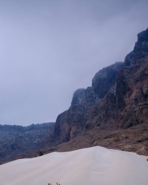 Yemen, Socotra 'daki Arher Sahili' ndeki yüksek kum tepesinin çarpıcı manzarası. Arka planda dramatik kaya kayalıkları var..