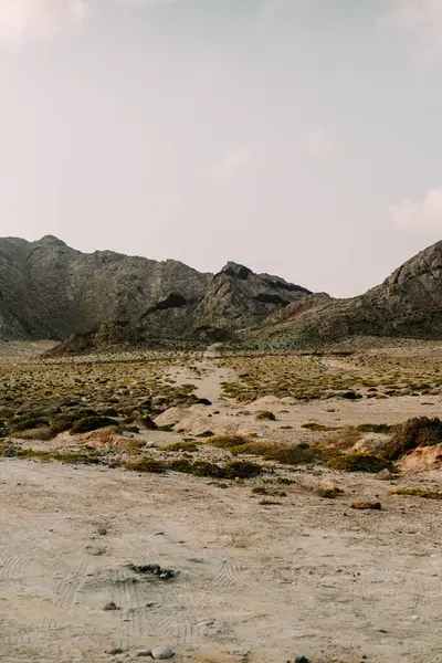 stock image View of rugged terrain and rocky mountains near Arher Beach in Socotra, Yemen, under a partly cloudy sky.