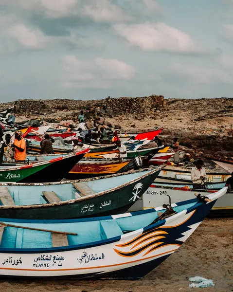Socotra, Yemen 'deki Arher Sahili' nin kıyısında dinlenen balıkçı tekneleri. Okyanus ve arka planda parçalı bulutlu bir gökyüzü..