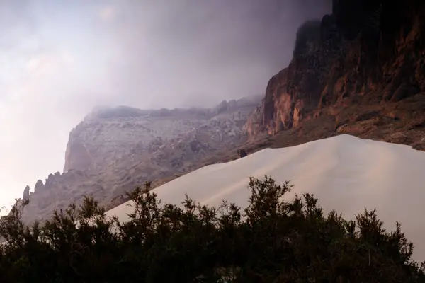 Yemen, Socotra 'daki Arher Sahili' ndeki yüksek kum tepesinin çarpıcı manzarası. Arka planda dramatik kaya kayalıkları var..