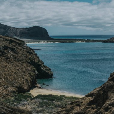 San Cristobal Adası, Galapagos, Ekvador 'daki Punta Pitt manzarası, engebeli uçurumlar, dingin turkuaz sular ve el değmemiş plajlar.