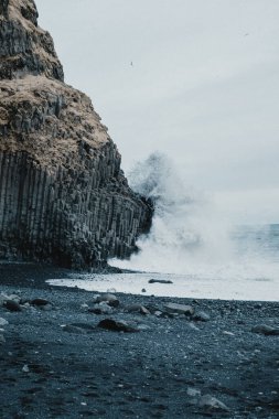 Dalgalar İzlanda 'nın güney sahilindeki Reynisfjara plajındaki bazalt sütunlara çarpıyor.