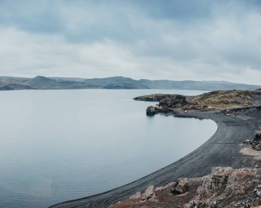 İzlanda 'nın Reykjanes Yarımadası' nın dramatik volkanik manzarasında, siyah kumlu kıyıları ve engebeli uçurumları olan Kleifarvatn Gölü 'nün huzurlu manzarası.