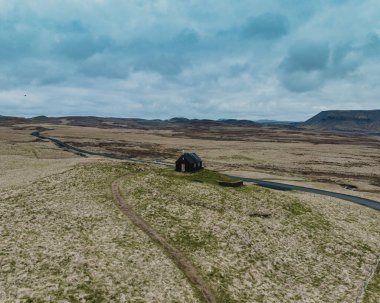 Reykjanes Yarımadası, İzlanda 'daki tarihi siyah ahşap kilise olan Krisuvikurkirkja' nın hava manzarası geniş volkanik alanlar ve geniş bir gökyüzü altında dönen yollarla çevrilidir.