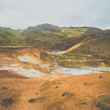 Seltun, Reykjanes Yarımadası, İzlanda 'daki jeotermal arazi, bulutlu bir gökyüzü altında canlı sülfürik yatakları, buharlı bacaları ve engebeli volkanik araziyi sergiliyor..