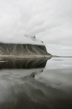 Güneydoğu İzlanda 'daki Vestrahorn dağının bulutlu bir günde sakin bir yansıması.