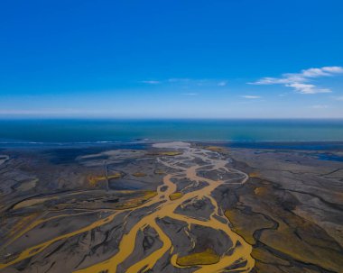 Güney İzlanda 'da okyanusu karşılayan örülmüş nehirlerin ve canlı kıyı şeritlerinin havadan görünüşü