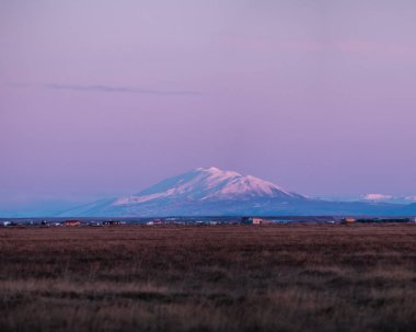 Hekla volcano during pink twilight, surrounded by fields in South Iceland. clipart