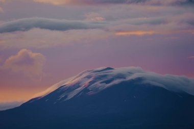 Günbatımında Hekla volkanı, canlı gökyüzü renkleriyle bulutlarla kaplı, Güney İzlanda