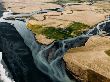Güney İzlanda 'da bir buzul nehrinin kara kumsalla buluşmasının havadan görüntüsü.