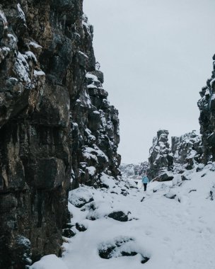 İzlanda 'daki Thingvellir Ulusal Parkı' nda karlı bir vadide yürüyüş yapan kişi..