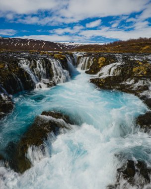 Bruarafoss waterfall with stunning turquoise waters under a bright sky in south Iceland clipart