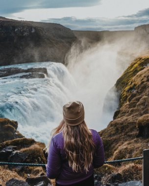 Güney İzlanda 'nın Altın Çemberi' ndeki güçlü Gulfoss şelalesine hayran bir gezgin.