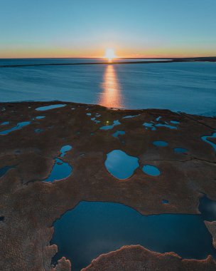 Güney İzlanda 'daki yansıtıcı su havuzlarıyla Olfusa nehir yatağının üzerinde gün batımı