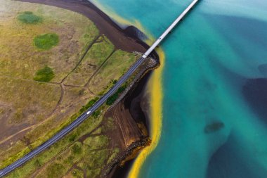 Olfusa Nehri 'nin canlı çökelti renkleri ve Güney İzlanda' daki köprüsünün havadan görünüşü