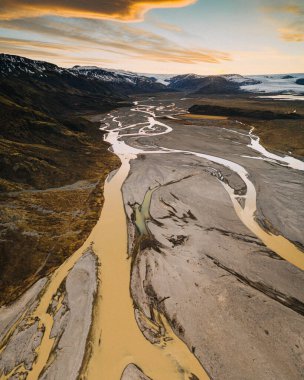 Güney İzlanda 'da gün batımında Hoffellsjokull buzulundan akan örülmüş nehirlerin hava manzarası