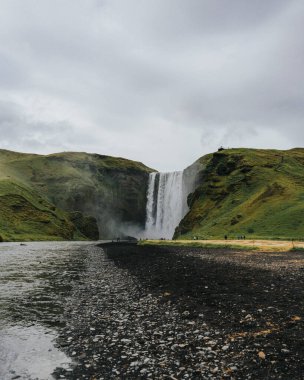 Güney İzlanda 'da kayalık nehir kıyılı Skogafoss şelalesi, doğal bir mucize.